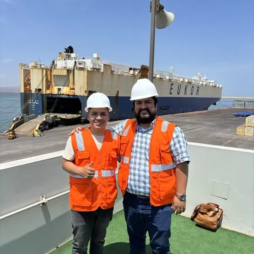 Giovanni Aaron junto a un colega en el puerto, frente a un buque EUKOR